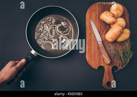 man putting frying pan Stock Photo