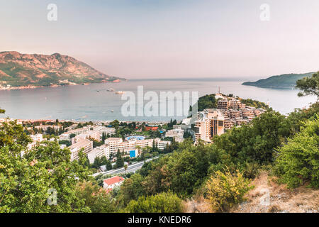 View of the beautiful bay, hotels and crowded beaches of the resort town of Becici in the rays of the sunset, Budva Riviera, Montenegro. Stock Photo