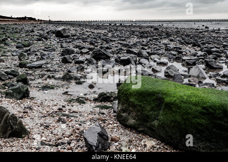 Large Green Stone on a rocky beach in Essex Stock Photo