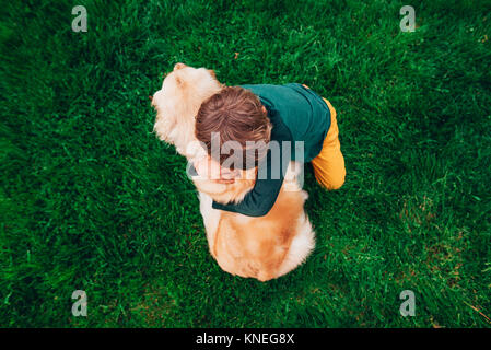Overhead view of a boy hugging his golden retriever dog Stock Photo