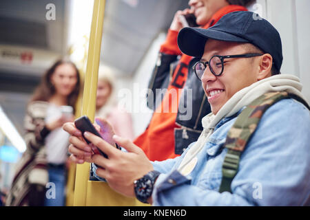Young man looking at smartphone on city tram Stock Photo