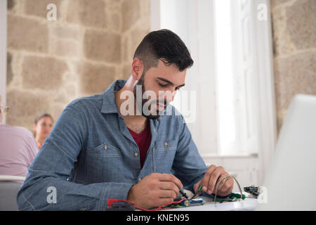 Young male computer technician repairing cable on office desk Stock Photo