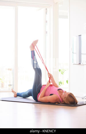 Pregnant young woman doing exercise in living room raising her leg Stock Photo
