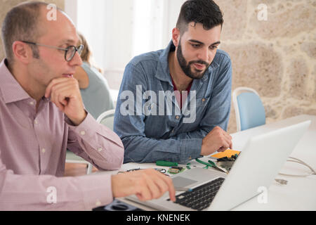 Computer technician repairing businessman's laptop on office desk Stock Photo
