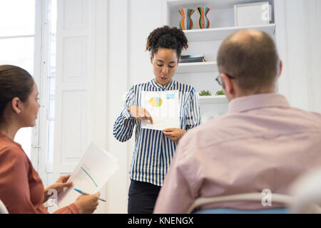 Businesswoman making pie chart presentation at boardroom table Stock Photo