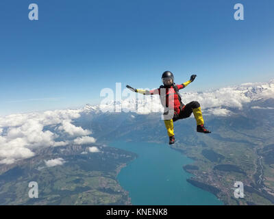 Female skydiver sitting up in free fall above clouds and lake Stock Photo