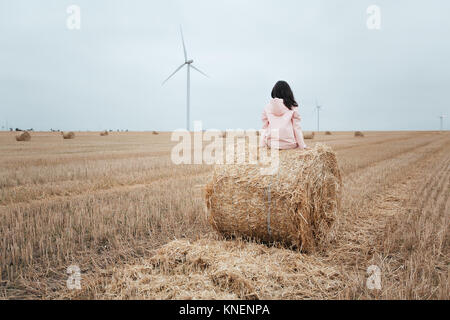 Woman in raincoat on hay bale, Odessa, Ukraine Stock Photo