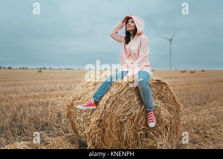 Woman in raincoat on hay bale, Odessa, Ukraine Stock Photo