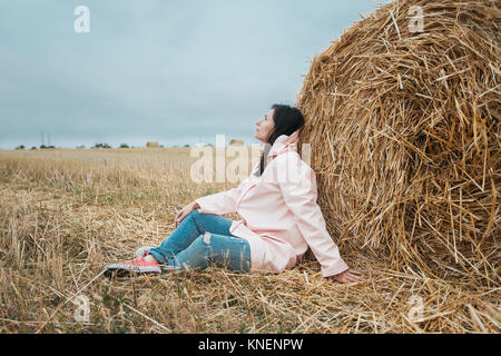 Woman in raincoat by hay bale, Odessa, Ukraine Stock Photo