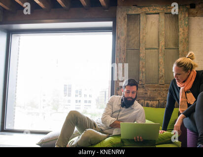 Colleagues on sofa using laptop Stock Photo