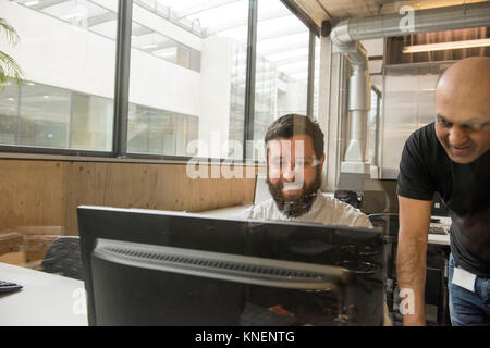 Colleagues in office looking at computer monitor Stock Photo