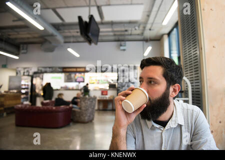 Man drinking from disposable cup in coffee shop Stock Photo