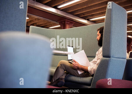 Side view of man in booth using laptop Stock Photo