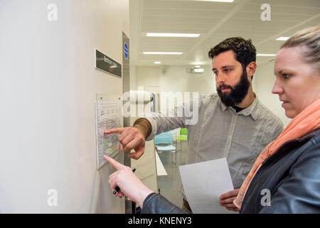 Tutor and student looking at timetable on seminar room door Stock Photo