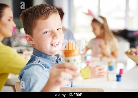 Portrait of boy holding painted hard boiled easter egg at table Stock Photo