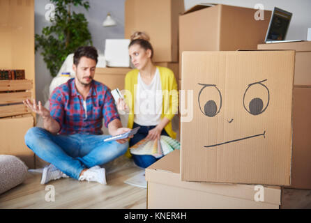 Young couple at home, surrounded by cardboard boxes, working out finances Stock Photo