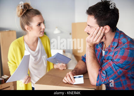 Young couple at home, surrounded by cardboard boxes, working out finances Stock Photo