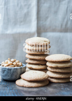 Stack of cookies with bowl of cashew nuts, close-up Stock Photo
