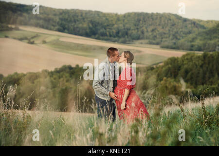 Romantic pregnant mid adult couple kissing in field Stock Photo