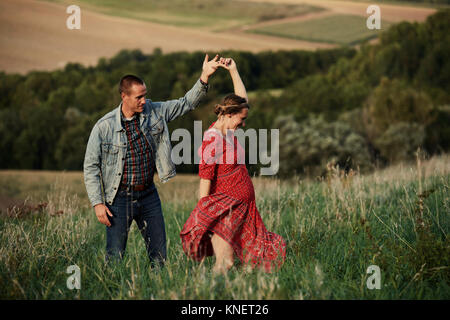 Romantic pregnant mid adult couple dancing in field Stock Photo