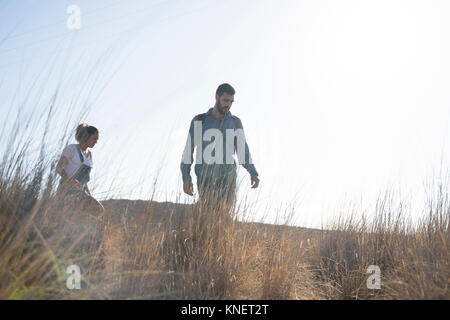 Young hiking couple hiking through long grass, Las Palmas, Canary Islands, Spain Stock Photo