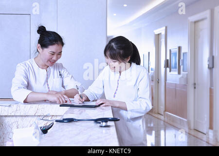Medical professionals at hospital reception desk using digital tablet Stock Photo