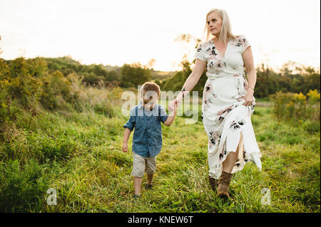 Mother and son walking on grass holding hands Stock Photo