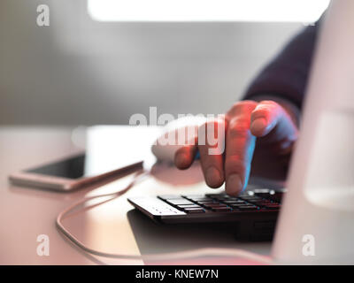 Computer hacker at laptop computer with mobile phone Stock Photo