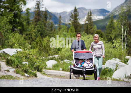 Senior couple and children in jogging stroller, summer day. Stock Photo