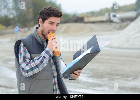 Man on construction site eating sandwich Stock Photo