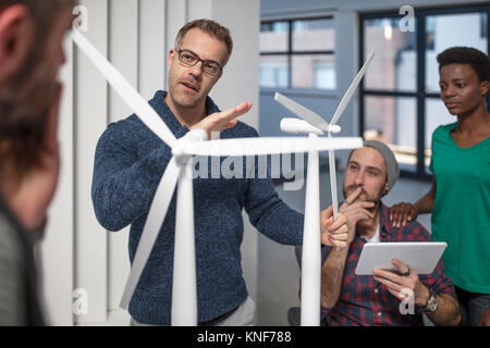 Colleagues discussing architectural model of wind turbine Stock Photo