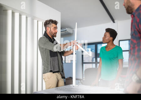 Colleagues discussing architectural model of wind turbine Stock Photo