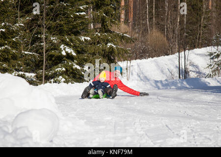 Man and son tobogganing in snow covered forest Stock Photo