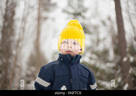 Boy in yellow knit hat in snow covered forest Stock Photo