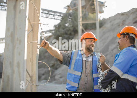 Two quarry workers in quarry, having discussion Stock Photo
