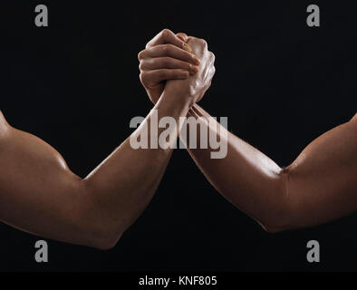 Arms of muscular women gripping hands Stock Photo