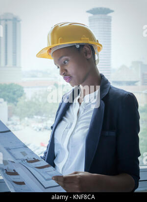 Woman in hard hat looking at building plans Stock Photo
