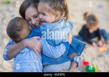 Mid adult woman hugging two young children Stock Photo