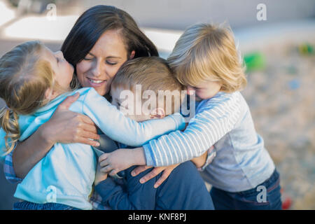 Mid adult woman hugging three young children Stock Photo