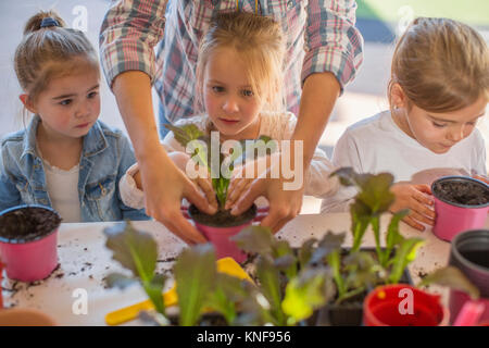 Mid adult woman helping young children with gardening activity Stock Photo
