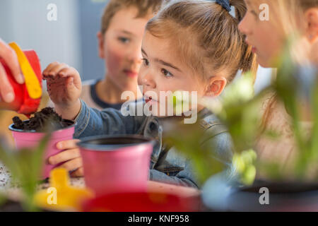 Mid adult woman helping young children with gardening activity, close-up Stock Photo
