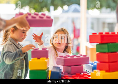 Two young children, outdoors, playing with foam building blocks Stock Photo