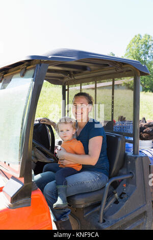 Portrait of female farmer and toddler daughter in truck on free range  organic farm Stock Photo
