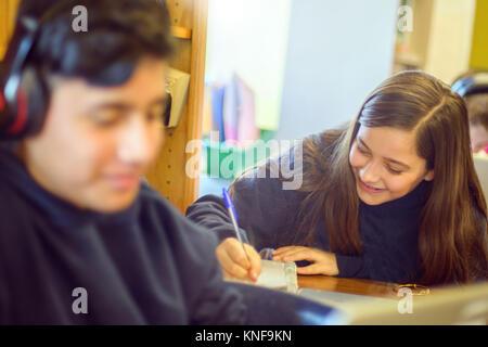 Teenage boy and girl doing schoolwork at classroom desks Stock Photo
