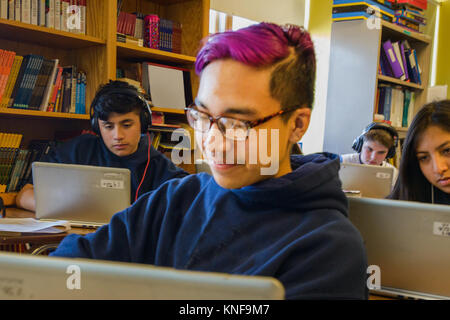 Teenage boys and girls doing schoolwork on laptops at classroom desks Stock Photo