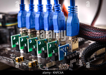Cryptocurrency mining rig PCIe riser extenders plugged to motherboard. Details of cryptocurrency bitcoin ethereum altcoin graphic card miner mining ri Stock Photo