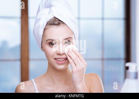 Pretty woman in towel turban removing eye makeup Stock Photo