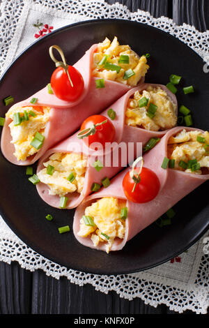 Delicious roll of ham stuffed with omelette close-up on a plate. Vertical top view from above Stock Photo