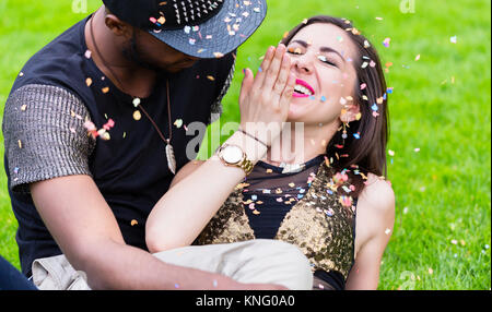 African Caucasian couple making fun and laughing on party in par Stock Photo