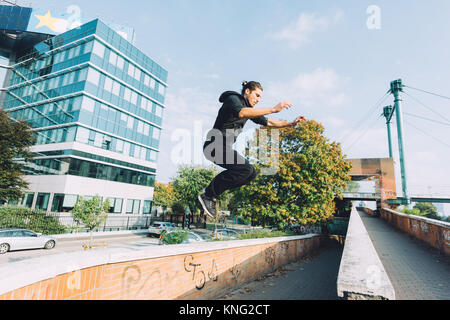 Young beautiful caucasian man doing parkour outdoor in the city in autumn - stunt, acrobat, trick concept Stock Photo